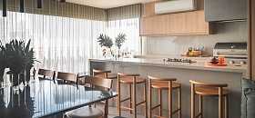   Neste projeto das arquitetas Danielle Dantas e Paula Passos, a península com banquetas é um convite à convivência, enquanto o home bar, a adega e a cervejeira reforçam o espírito festeiro da família. Com o suporte da churrasqueira, do cooktop e da coifa, tudo funciona de forma prática e integrada à sala de jantar, sem abrir mão do conforto | Projeto Dantas & Passos Arquitetura | Foto: Henrique Ribeiro