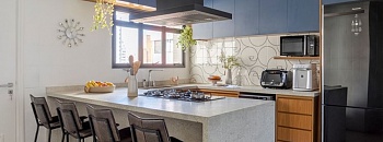 Neste projeto, o arquiteto Paulo Tripoloni brinca com a paleta cromática trazendo na marcenaria laminada um azul mineral que harmoniza com o granito branco-itaúnas escovado em destaque na bancada | Projeto: Atelier de Arquitetura Paulo Tripoloni | Foto: Rafael Renzo