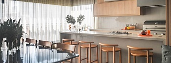   Neste projeto das arquitetas Danielle Dantas e Paula Passos, a península com banquetas é um convite à convivência, enquanto o home bar, a adega e a cervejeira reforçam o espírito festeiro da família. Com o suporte da churrasqueira, do cooktop e da coifa, tudo funciona de forma prática e integrada à sala de jantar, sem abrir mão do conforto | Projeto Dantas & Passos Arquitetura | Foto: Henrique Ribeiro