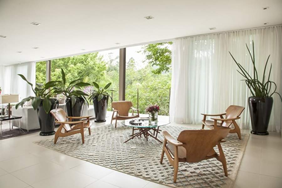 Na brasilidade do living integrado da resid&ecirc;ncia, a mesa de centro Guaimb&ecirc;, do designer Paulo Alves, recebeu, em seu entorno as poltronas DIZ, assinadas por S&eacute;rgio Rodrigues. No projeto realizado pelo escrit&oacute;rio Macedo e Covolo, a proposta foi elaborar um espa&ccedil;o perfeito para bate-papo regado &agrave; degusta&ccedil;&atilde;o de vinhos | Foto: Eduardo Pozella