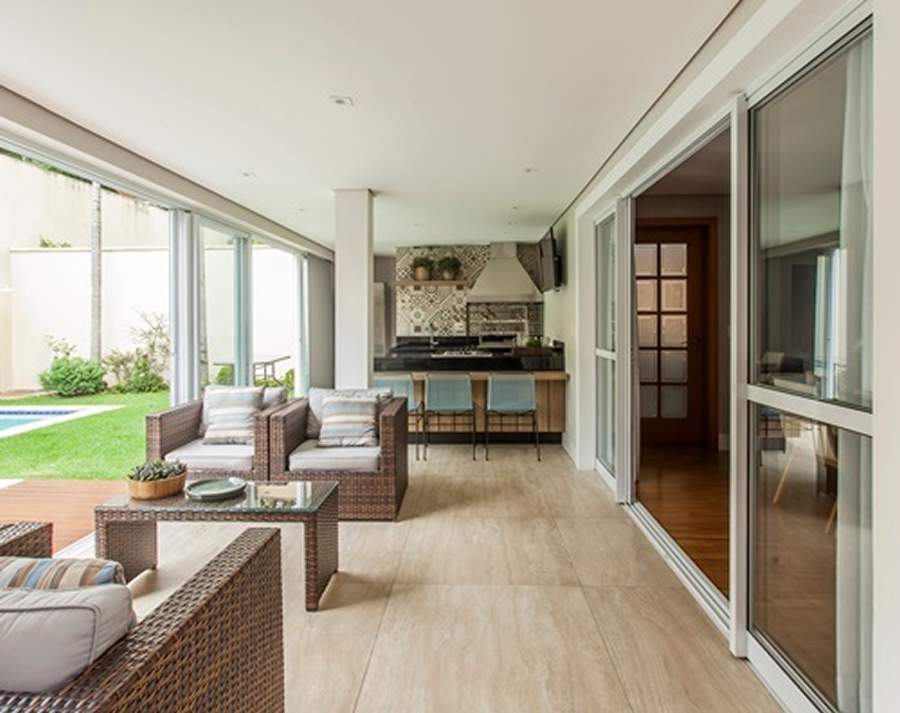 Nesse projeto realizado pela arquiteta Giselle Macedo e a designer de interiores Patricia Covolo, a churrasqueira da &aacute;rea gourmet &eacute; acompanhada por um living externo contempor&acirc;neo e aconchegante para os momentos em fam&iacute;lia. O cooktop e a bancada em granito oferecem a possibilidade de se cozinhar enquanto interage com o restante da fam&iacute;lia. | Foto: Eduardo Pozella