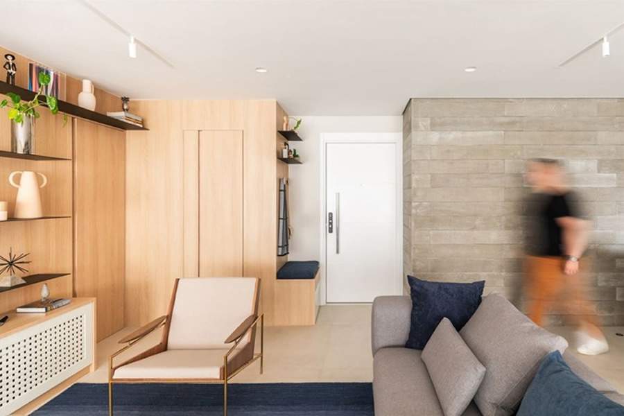 No projeto de seu próprio apartamento, o arquiteto Bruno Moraes elaborou um móvel, bem ao lado da porta principal, que é um espaço para sentar-se, calçar e tirar os sapatos (e com nicho para guardá-los), além de conter um gaveteiro e dois ganchos para pendurar casacos e bolsas | Projeto BMA Studio | Foto: Guilherme Pucci