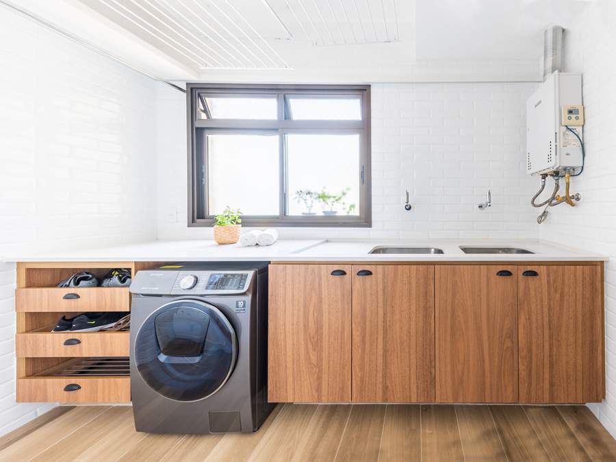 Neste apartamento assinado pela arquiteta J&uacute;lia Guadix, a marcenaria planejada da &aacute;rea de servi&ccedil;o possibilitou que tudo ficasse organizado no ambiente. Al&eacute;m dos arm&aacute;rios com grande profundidade, ao lado da lava e seca, que foi embutida no projeto, tr&ecirc;s gavetas recebem os sapatos que foram limpos e precisam secar | Foto: Guilherme Pucci 