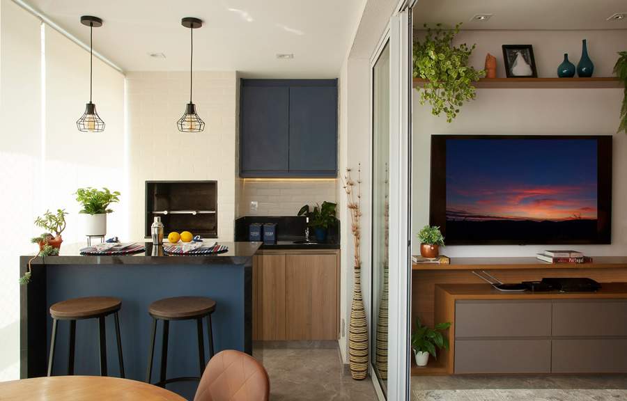 A dupla de banquetas de ferro fundido com assento de madeira foi a escolha das profissionais da Tesak Arquitetura para essa varanda gourmet, atendendo perfeitamente a &aacute;rea da churrasqueira. Foto: Lu&iacute;s Gomes