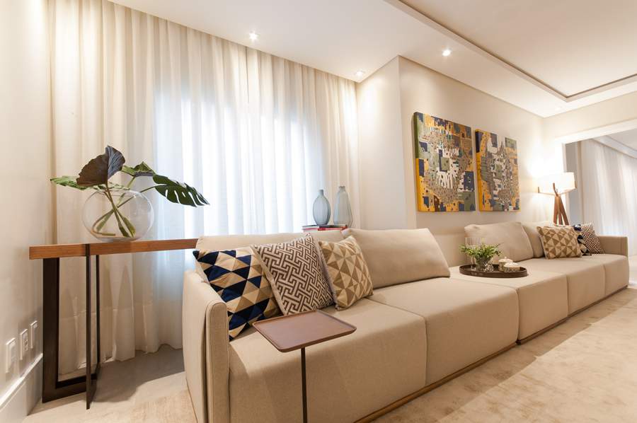 Sof&aacute; amplo &eacute; um bom investimento para os moradores que sempre recebem visitas. Neste projeto de Paiva e Passarini, o m&oacute;vel eleito para o projeto combina uma estrutura firme e, ainda assim, confort&aacute;vel. Almofadas com capas variadas e cortina definem o mood do living | Projeto: Paiva e Passarini - Arquitetura | Foto: Xavier Neto