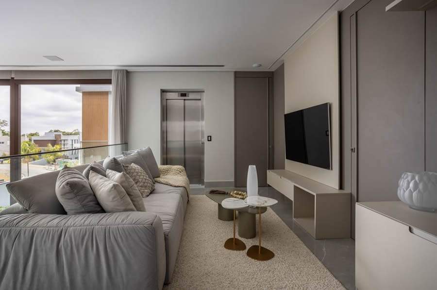  Nessa residência, o espaço de circulação acessa os dormitórios da família e foi projetado para ser uma sala íntima da família. Assim, os profissionais do escritório Meneghisso &amp; Pasquotto Arquitetura definiram um sofá aconchegante para os momentos antes da hora de dormir | Foto: JP Image