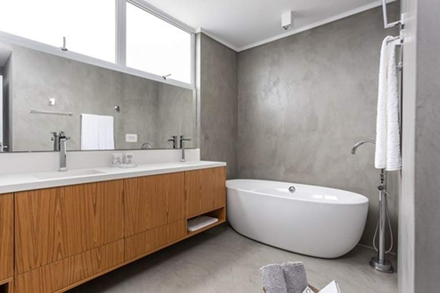 No banheiro do apartamento que pertence a um jogador de basquete, a arquiteta Andrea Camillo optou por uma banheira de imers&atilde;o em lou&ccedil;a branca, que combinou perfeitamente com a pegada industrial estabelecida no projeto. Ela ajuda na miss&atilde;o de aliviar as dores musculares proveniente da rotina corrida, estressante e que testa constantemente os limites f&iacute;sicos do corpo de seu morador. | Foto: JP Image