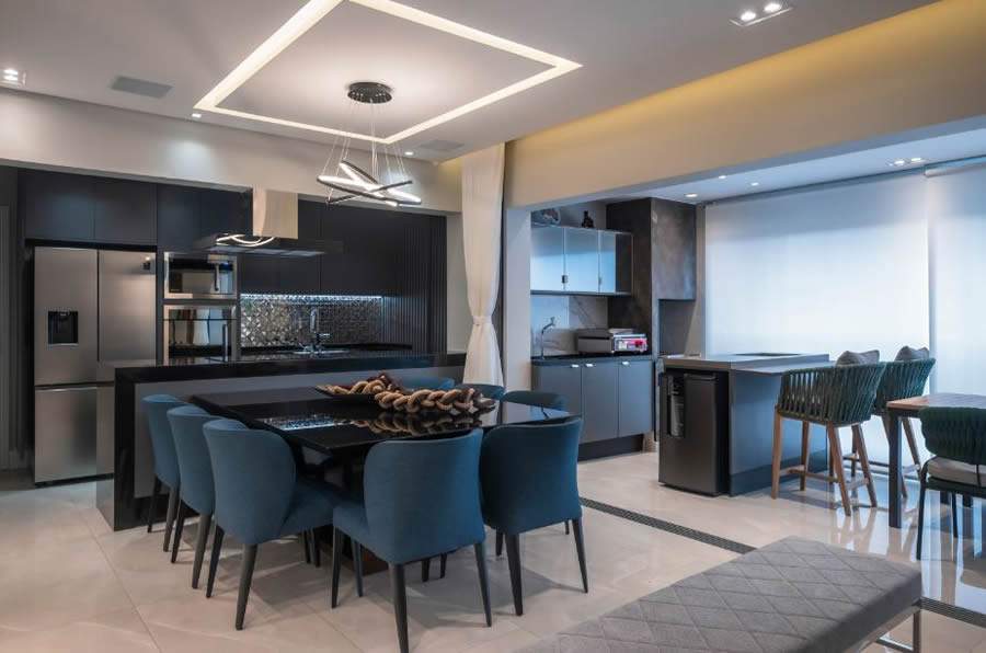 Na &aacute;rea social integrada, executada pelo escrit&oacute;rio PB Arquitetura, al&eacute;m do LED embutido no forro de gesso, a fita de destaca na estrutura da marcenaria da cozinha, iluminando, de maneira eficiente e discreta, o front&atilde;o da pia | Foto: Henrique Ribeiro