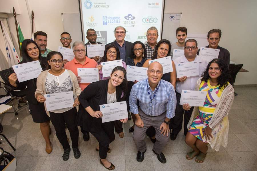 Formandos da primeira turma da Universidade Aconseg com seus diplomas do curso de Seguro Sa&uacute;de Suplementar.