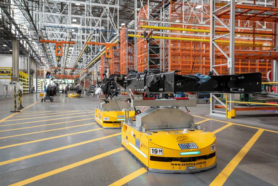 Figure 1: 1 ou 2 pares de AGVs acoplados transportam o enorme chassi de ônibus através da linha de montagem.