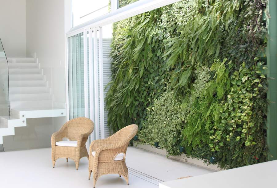 O jardim vertical vistoso e as cadeiras de material natural marcam a est&eacute;tica do Urban Jungle em projeto de Cezar Scarpato