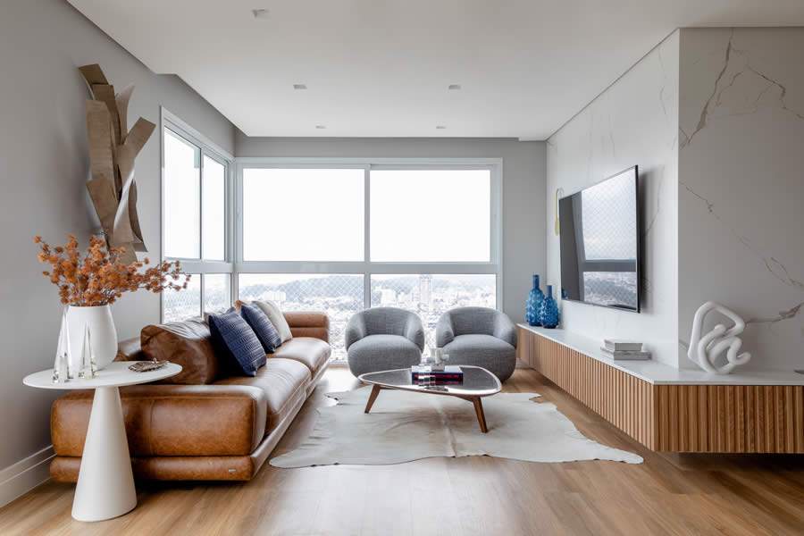 Harmonia no living: o efeito amadeirado do piso vin&iacute;lico se completa com o mobili&aacute;rio &ndash; o sof&aacute; em couro caramelo e o rack ripado, em &lsquo;L&rsquo; | Foto: F&aacute;bio Severo