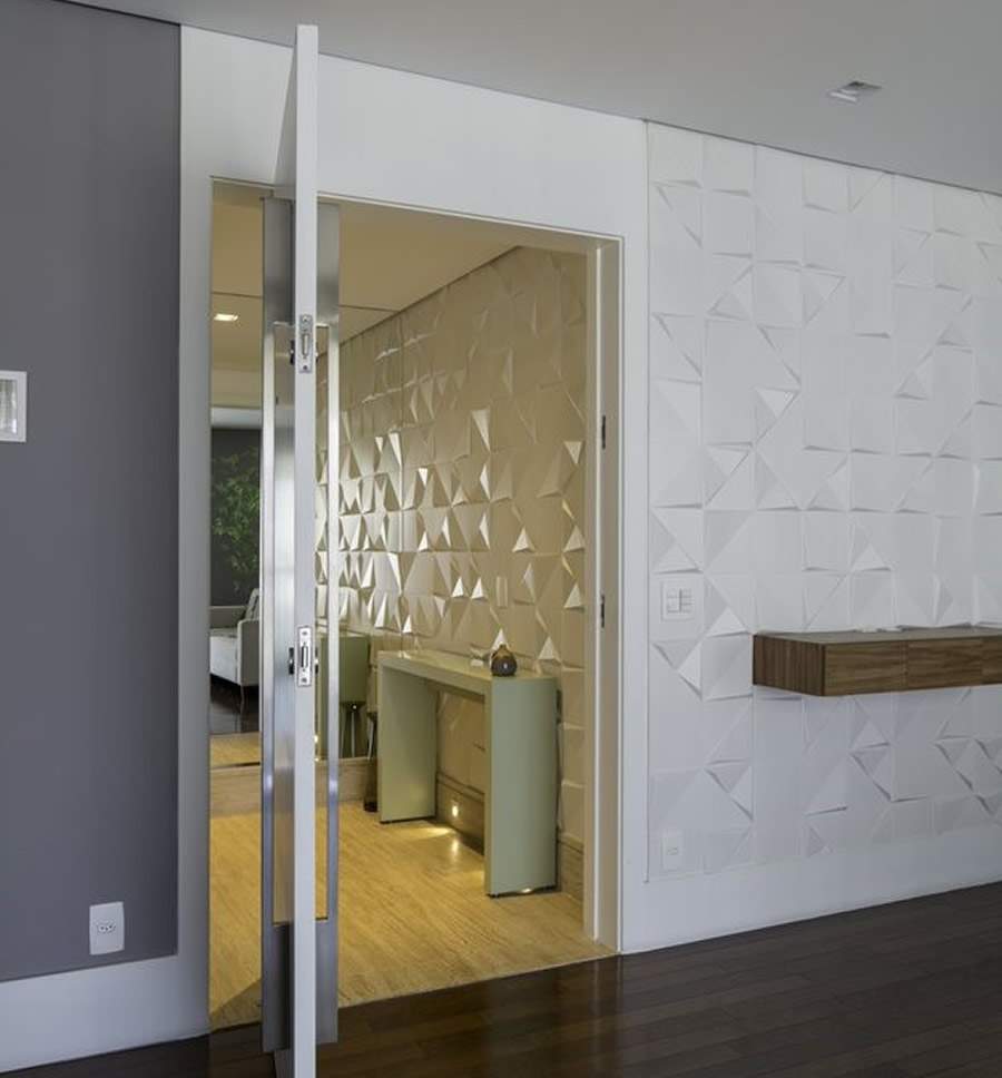 Na entrada do apartamento, o revestimento cerâmico, o revestimento da linha Tangram, da Portobello, compõe o hall de entrada e, na sala de estar, contrapõe o cinza escuro presente nas demais paredes |Projeto Raízes Arquitetos | Foto: Edson Ferreira