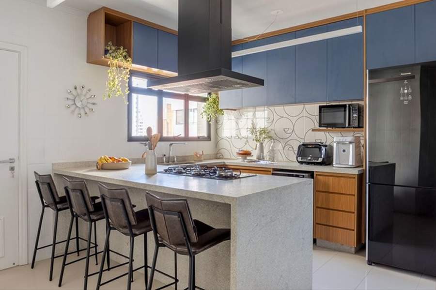 Neste projeto, o arquiteto Paulo Tripoloni brinca com a paleta crom&aacute;tica trazendo na marcenaria laminada um azul mineral que harmoniza com o granito branco-ita&uacute;nas escovado em destaque na bancada | Projeto: Atelier de Arquitetura Paulo Tripoloni | Foto: Rafael Renzo