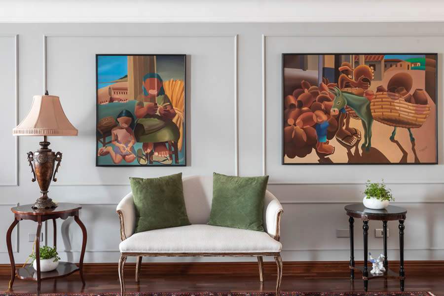 Neste projeto, a arquiteta Marta Martins criou uma moldura ainda maior nas obras do acervo pessoal da cliente ao instalar boiserie na parede, acrescentando uma leveza ao olhar enquanto preservou as mesinhas e o abajur em tons mais fortes. O pequeno sof&aacute; recebeu um novo estofado | Foto: Thiago Travesso