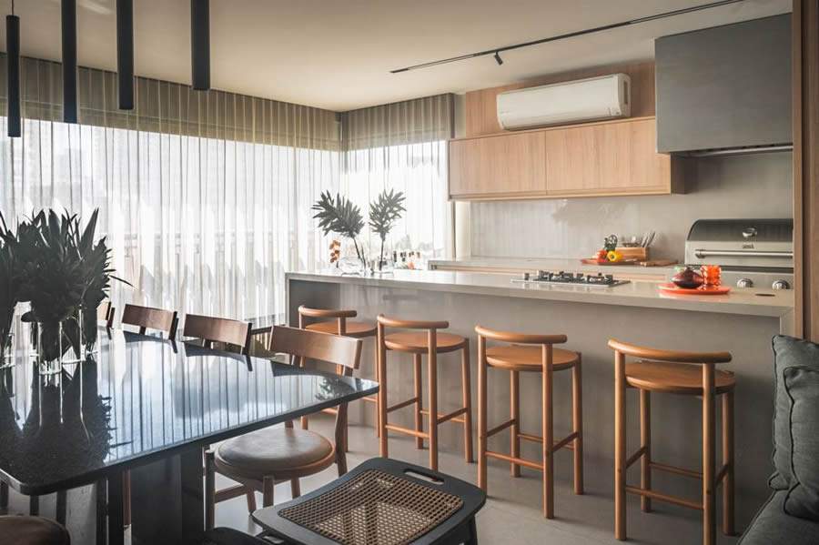   Neste projeto das arquitetas Danielle Dantas e Paula Passos, a pen&iacute;nsula com banquetas &eacute; um convite &agrave; conviv&ecirc;ncia, enquanto o home bar, a adega e a cervejeira refor&ccedil;am o esp&iacute;rito festeiro da fam&iacute;lia. Com o suporte da churrasqueira, do cooktop e da coifa, tudo funciona de forma pr&aacute;tica e integrada &agrave; sala de jantar, sem abrir m&atilde;o do conforto | Projeto Dantas &amp; Passos Arquitetura | Foto: Henrique Ribeiro